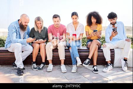 Group of serious people addicted technology. Friends using phone dependency social media and technology insane young colleague unhappy Stock Photo