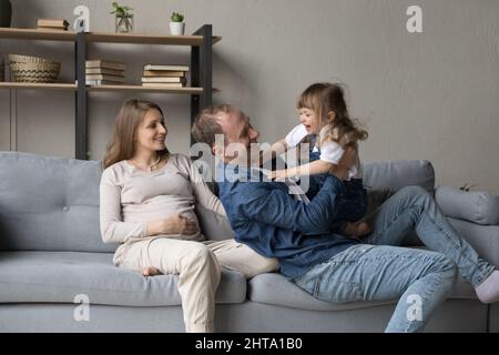 Happy cheerful dad tickling playful excited little daughter girl Stock Photo