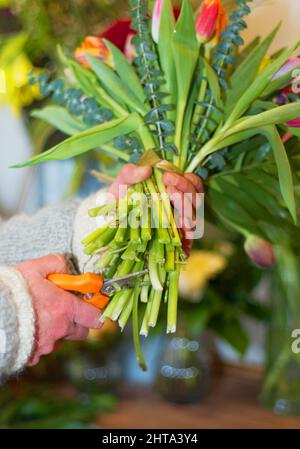 The final touches. Cropped view of a florists hands as she prepares a bouquet of flowers. Stock Photo