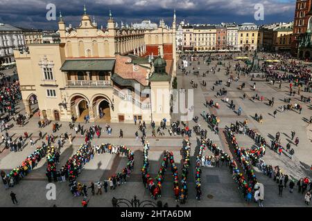 Krakow, Poland. 27th Feb, 2022. A group of Italian students formed a colorful 'no war' sign at the Main Market Square during the demonstration. An anti-war protest by the Ukrainian community, the Poles and Belarusians who support them. Since the beginning of the Russian invasion of Ukraine, demonstrations have taken place daily and lasted many hours. Participants are constantly trying to reach as many people as possible with their message, including employees of the US and German consulates, in front of which they also stop several times a day. Credit: SOPA Images Limited/Alamy Live News Stock Photo