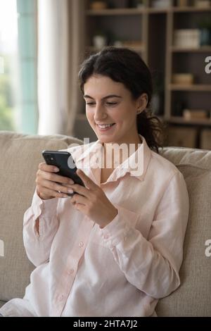 Happy attractive millennial Hispanic woman using smartphone. Stock Photo