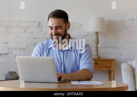 Young handsome freelancer man sit at table using laptop Stock Photo