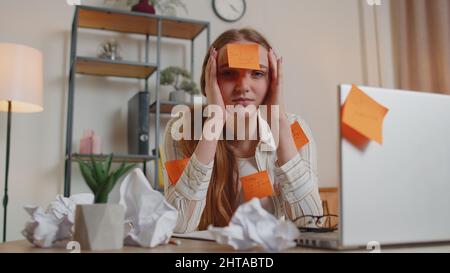 Exhausted woman freelancer with pasted stickers using laptop having concentration problem in office Stock Photo