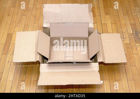 Empty open cardboard boxes on wooden floor interior Stock Photo