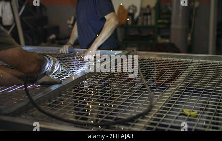 Close-up of unrecognizable welder's hands with blowtorch, welding a metal structure. Stock Photo