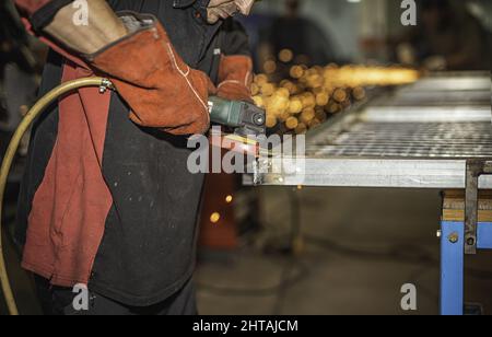 Close-up of an unrecognizable Caucasian man using a grinder with grinding wheel. Stock Photo