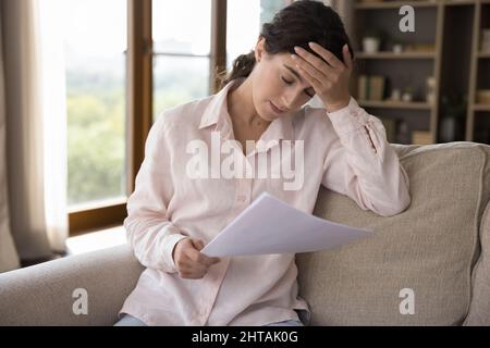 Frustrated millennial Hispanic woman feeling stressed reading letter. Stock Photo