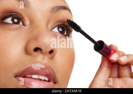 Artist at work. Cropped shot of a gorgeous young woman applying mascara in a studio-isolated on white. Stock Photo