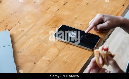 CHIANG MAI. THAILAND. FEB 26, 2022. A woman holds Apple iPhone 13 with facebook logo on the screen from meta. Facebook is a largest social network and Stock Photo