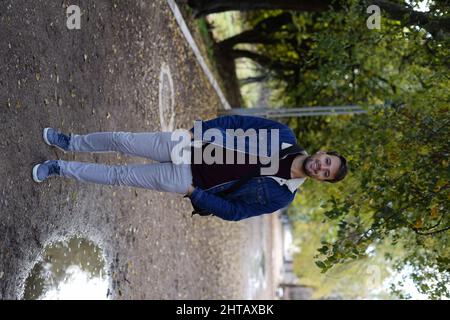 Cheerful young White guy in a park dressed casually Stock Photo