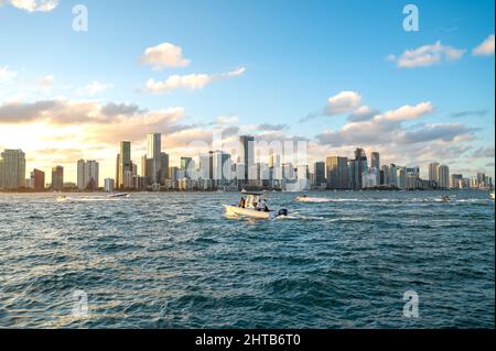 Sunset downtown travel and luxury Miami / Brickell area with cloudy blue sky’s and a fishing boat in the water. Biscayne bay next to port of Miami. Stock Photo