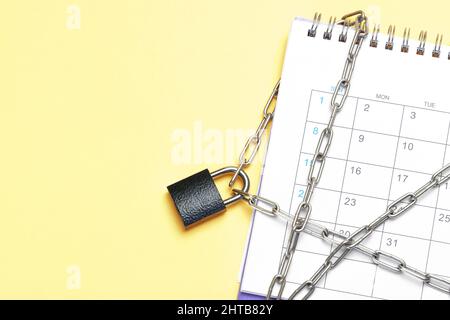 Calendar is wrapped in a chain and closed with a padlock. Yellow background. Template Copy space for text. mock-up. Stock Photo