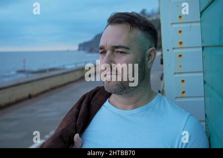 Bearded handsome middle aged Caucasian male leaning on the wall on the street Stock Photo
