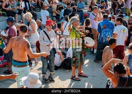 Montreal, Canada - June, 2018: Man playing percussion with djembe drum bongo in the dancing crowd. Stock Photo