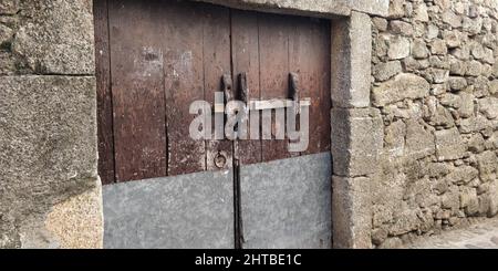 Very old gate with lock in a wall made from big rocks Stock Photo