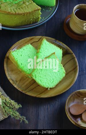 Bolu pandan or Pandan Chiffon Cake, served with tea on dark wooden background. Selective focus. Stock Photo