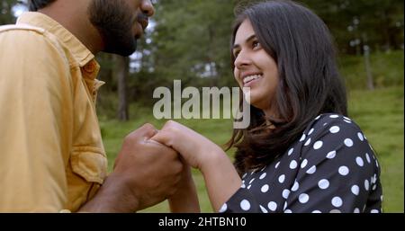 Shallow focus of a lovely South Asian young adult couple holding hands and dancing in a park Stock Photo