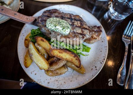 Top down view of a delectable steak frites dinner on a wooden table inside a restaurant Stock Photo