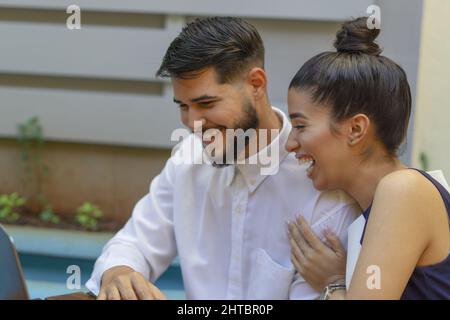 Closeup of a happy couple working on a laptop in a cafe with a blurry background Stock Photo