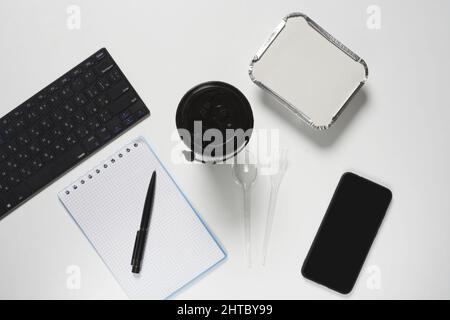 A top view shot of a keyboard, a notebook and pen and a phone on a white background Stock Photo