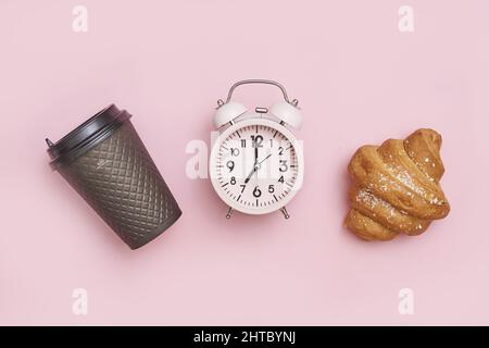 Vintage alarm clock with a cup of coffee and a fresh croissant on the pink surface Stock Photo