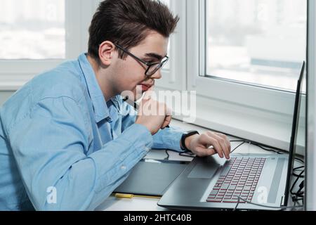young male designer in glasses working on a professional graphics tablet with a pen Stock Photo