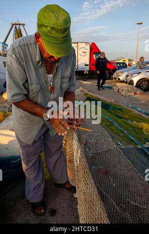 Europa, Italia, Sardegna, Porto Torres, fisherman repairing broken net Stock Photo