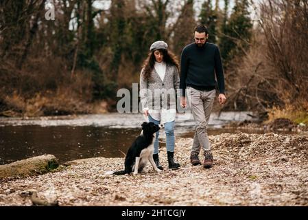 A Caucasian pregnant woman and her man walking with a dog in the park and doing some maternity photoshoot. Stock Photo