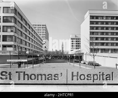 St Thomas' Hospital, Lambeth Palace Road, Lambeth, London, 28/02/1977. Looking along the central avenue between four new blocks at St Thomas' Hospital, with the hospital sign in the foreground, from the east. Work on Phase II of a rebuilding project at St Thomas' Hospital was undertaken by Laing and began in early 1969 and was completed in 1975. This phase included a new ward block, operating suites, outpatients' department, research institute, nurses' home and nurses' training school. Phase I had been completed in 1966 by Sir Robert McAlpine and Sons; Phase III of the project was planned to b