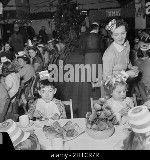 Thurleigh Airfield, Thurleigh, Bedfordfordshire, 19/12/1953. Children wearing party hats and having tea at a children's party. This photograph shows a children's party that was organised by Laing's Welfare staff and members of the Committee for the children of staff working on the Thurleigh Airfield project. The party was held in the Camp Theatre and included clowns, games, a film show, presents from Santa Claus and tea for sixty children. Stock Photo