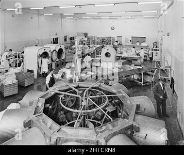 West Cumberland Hospital, Homewood Road, Homewood, Whitehaven, Copeland, Cumbria, 27/08/1964. Workers washing and pressing bed linen in the laundry at West Cumberland Hospital. Built during the first phase of construction at the site along with the boiler house and workshops, the laundry could handle 45,000 articles a week and serviced a number of hospitals in the region. This photograph appeared in the December 1964 issue of Team Spirit, the Laing company newsletter. Stock Photo