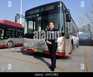 (220228) -- TIANJIN, Feb. 28, 2022 (Xinhua) -- Wang Yan poses for a photo at a bus stop in north China's Tianjin, Feb. 24, 2022. Tianjin bus driver Wang Yan is a National People's Congress (NPC) deputy. Since taking on her duties in 2018, Wang has continued to submit suggestions to the NPC, covering a variety of areas, such as transportation and health care. As a bus driver, she makes the most of her job, listening to her passengers' opinions, while formulating suggestions that can have an influence on government policies. This year is the last year of her term of NPC deputy, Wang will pu Stock Photo
