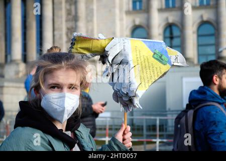 Woman in face mask with bird made of newspaper protests against the war in Ukraine. Stock Photo