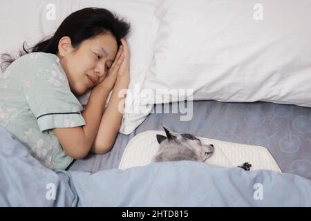 Happy smiling woman sleeping with a dog in bed at home. Stock Photo