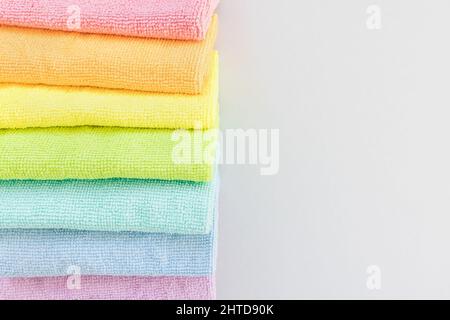 New folded microfiber cloth for cleaning in seven rainbow colors on gray background. Cleaning micro fabric towels for dusting and polishing. Domestic household cleaning service concept. Top view, closeup. copy space Stock Photo