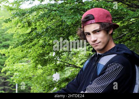 Cool Argentinian young male wearing a cap and jacket looking at the camera Stock Photo