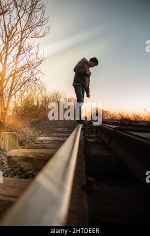 Vertical shot of a Caucasian (White) man standing on train tracks Stock Photo