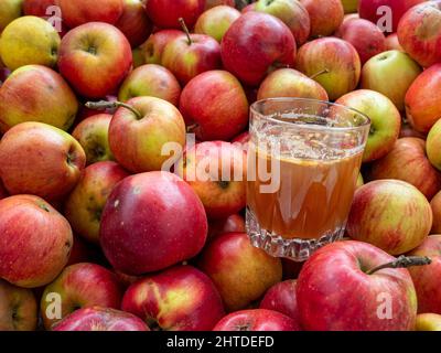 Glass with apple juice on a stack of apples Stock Photo