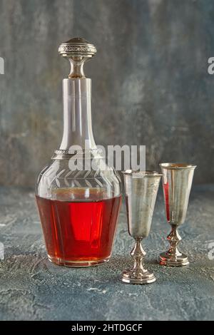 Still life, vintage decanter in silver and glass with wine and two glasses. Stock Photo