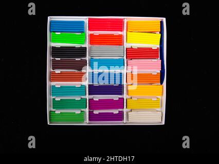 Open box with multi-colored plasticine on a black background. Close-up, preschool Stock Photo