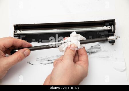 Cleaning the details of the laser cartridge printer from the remnants of the old toner on a white background. Refilling the Toner Cartridge Stock Photo