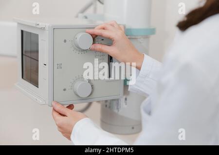 Hospital Radiology Room. Xray machine for fluorography. Doctor radiologist in gown adjusting the X-ray machine for radiography. Medical equipment Stock Photo