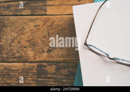 A top view of pile of books with optics on top on a wooden table Stock Photo