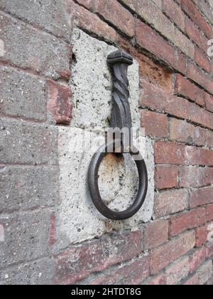 Ancient iron hoop hanging on stone wall Stock Photo