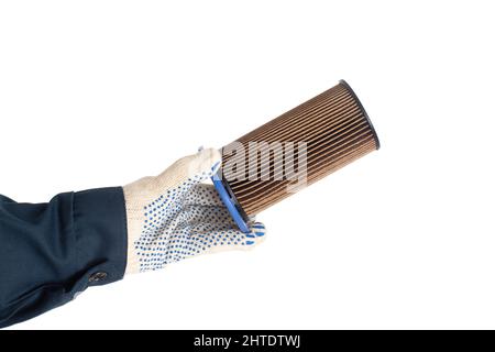 An auto mechanic holds an old dirty fuel filter in his hand. Fuel filter replacement concept, low-quality fuel, white background, isolate, equipment Stock Photo