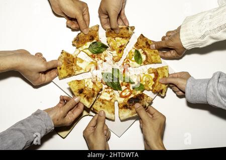 Top view of hands taking slices from the whole pizza Stock Photo