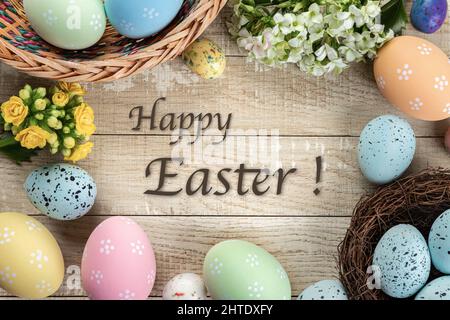 Easter border of colored easter eggs and flowers on a rustic wooden background with Happy Easter text Stock Photo
