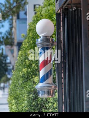 Los Angeles, CA, USA - February 25, 2022: Close up of a traditional Barber’s Pole in front of a barber shop in Los Angeles, CA. Stock Photo