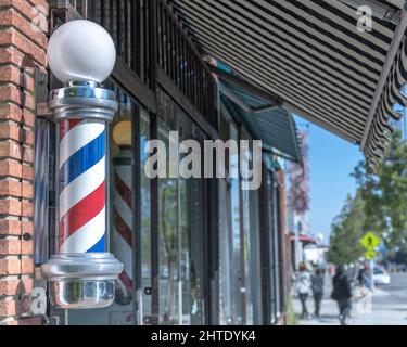 Los Angeles, CA, USA - February 25, 2022: Close up of a traditional Barber’s Pole in front of a barber shop in Los Angeles, CA. Stock Photo