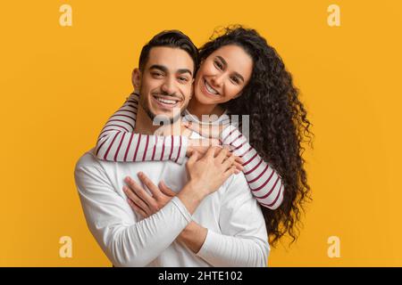 Happy Millennials. Beautiful Smiling Arab Couple Embracing And Looking At Camera Stock Photo